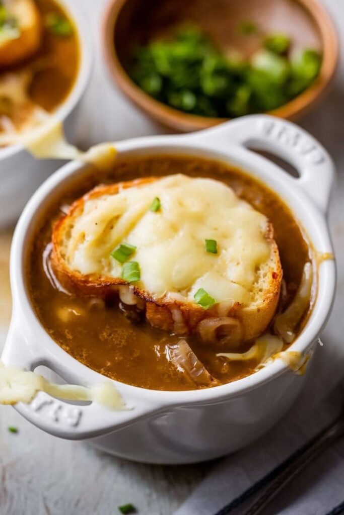 Bowl of French onion soup topped with melted cheese and bread, garnished with green onions.