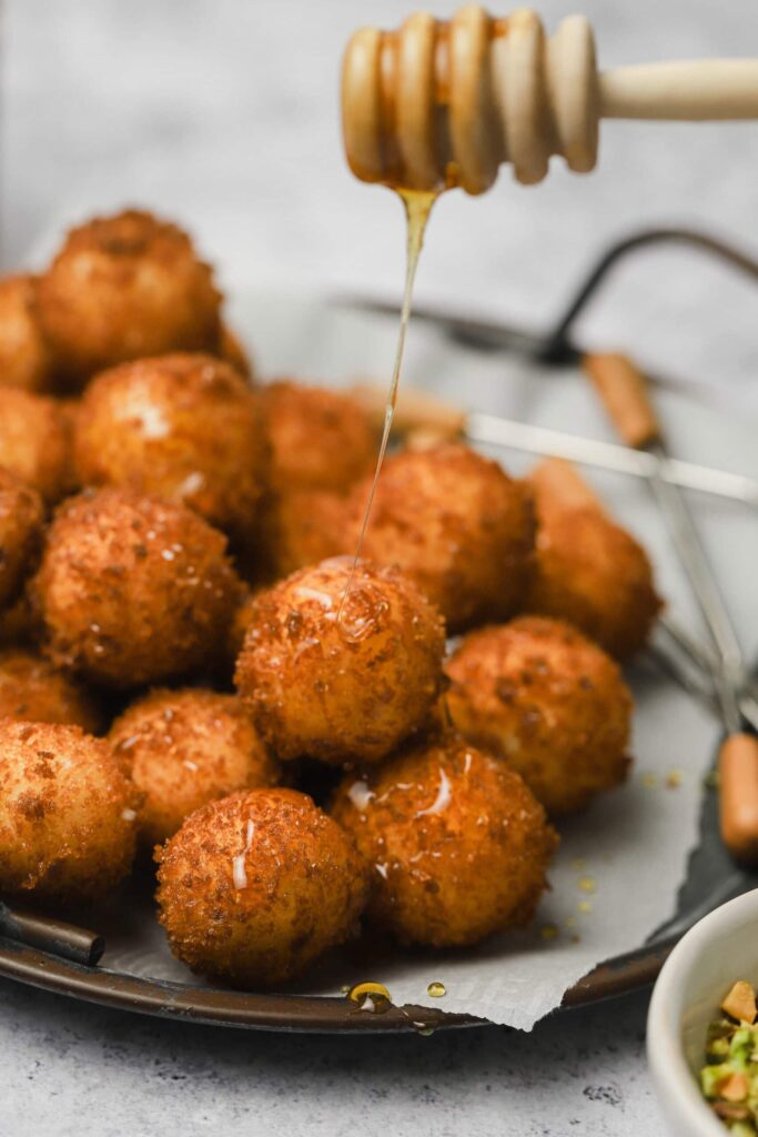 Fried-goat-cheese-balls-4-scaled - Step-by-Step Guide to Perfect Fried Goat Cheese Balls Golden fried cheese balls drizzled with honey on a plate, creating a sweet and savory appetizer.