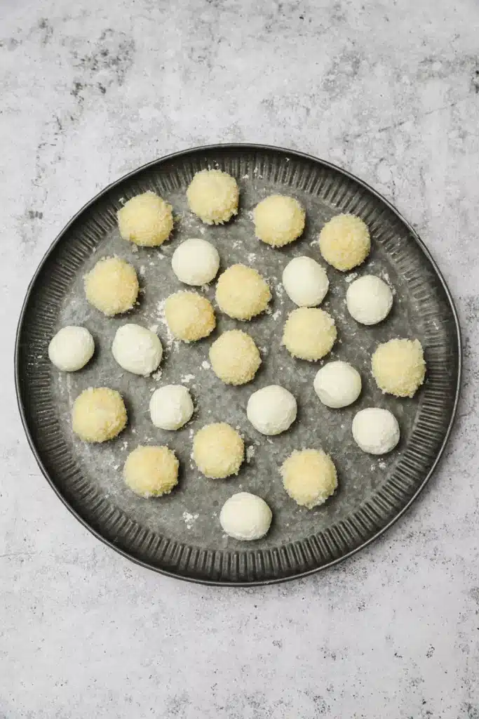 Fried-goat-cheese-balls-6 - Step-by-Step Guide to Perfect Fried Goat Cheese Balls Round cheese balls on a metal tray ready for baking, arranged in a neat pattern on a gray surface.