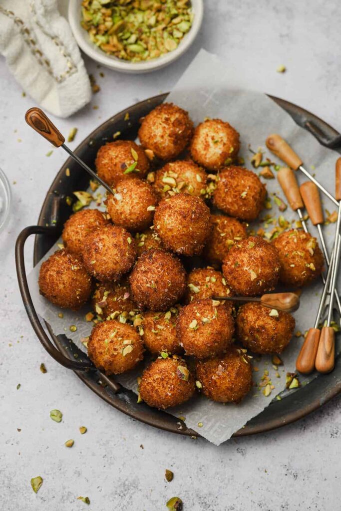 Fried-goat-cheese-balls-with-pistachios - Step-by-Step Guide to Perfect Fried Goat Cheese Balls Golden fried cheese balls with crushed pistachios on a platter, ready to serve with skewers. Fried Goat Cheese Balls