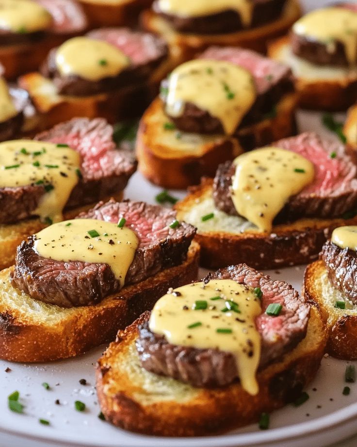 Sliced steak bruschetta with creamy sauce and chives on toasted bread for a delicious appetizer display.