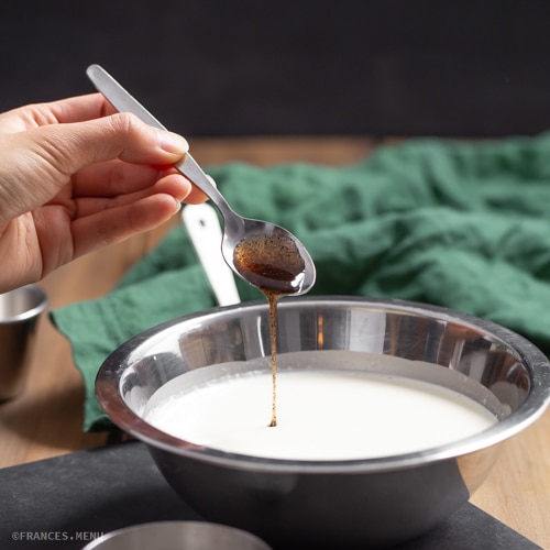 Adding vanilla extract to a bowl of milk for a baking recipe.
