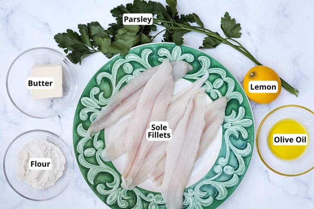 Ingredients-for-Sole-Meuniere - Enjoy a French Favorite: Sole Meunière & Potatoes Sole fillets on a plate with butter, flour, parsley, lemon, and olive oil on a marble surface, perfect for cooking.