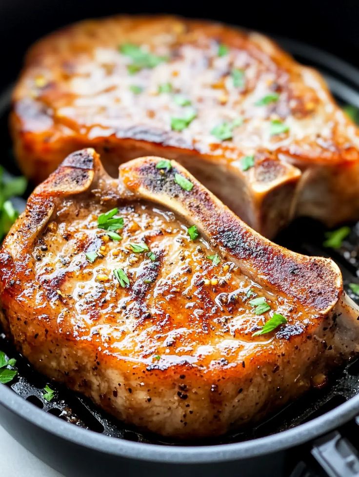 Juicy grilled pork chops with herbs, seared to perfection in a skillet, showcasing a delicious and savory meal.