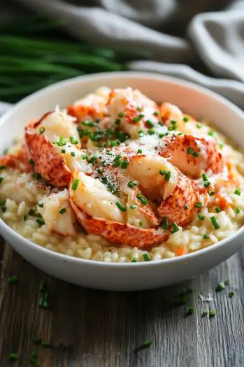 Gourmet lobster risotto garnished with fresh herbs in a white bowl on a wooden table.
