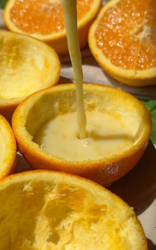 Orange halves filled with creamy dessert, showcasing fresh citrus and texture.