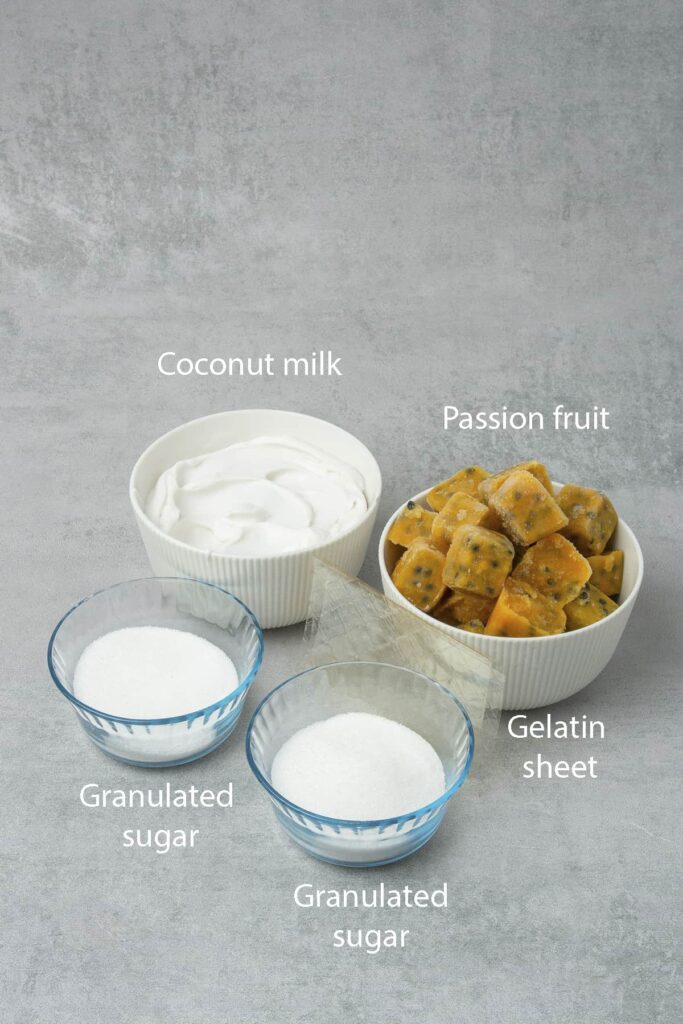 Passion-fruit-panna-cotta-ingredients-1 - Silky, Tropical Coconut & Passion Fruit Panna Cotta Coconut milk, passion fruit, gelatin sheets, and granulated sugar ingredients on a gray background.