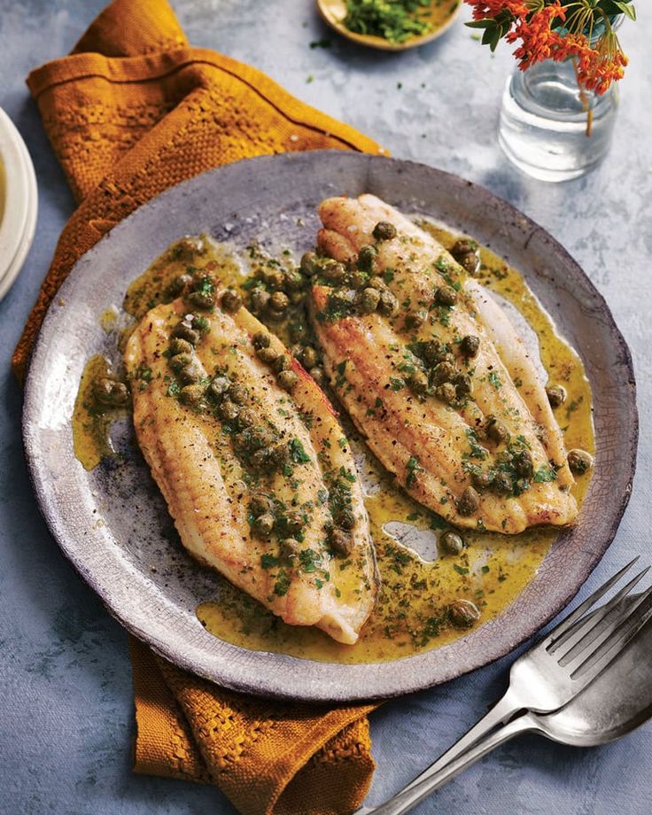 Sole meuniere - Enjoy a French Favorite: Sole Meunière & Potatoes Pan-seared fish fillets with capers atop a rustic plate, garnished with herbs on a textured table setting.