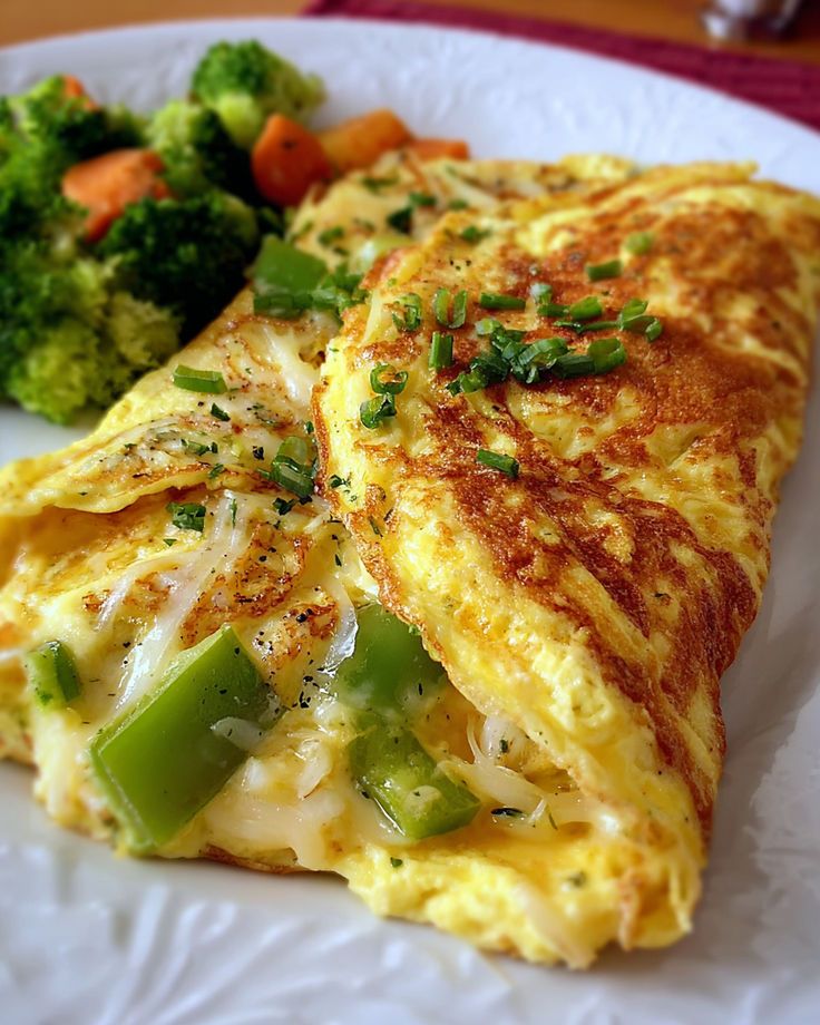Cheese and pepper omelette with fresh veggies on a plate, garnished with herbs for a healthy breakfast option.