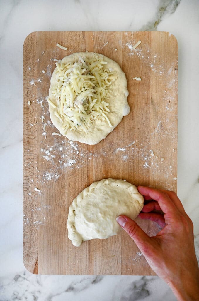 Making homemade calzones with cheese, captured on a wooden cutting board for authentic culinary kitchen vibes.