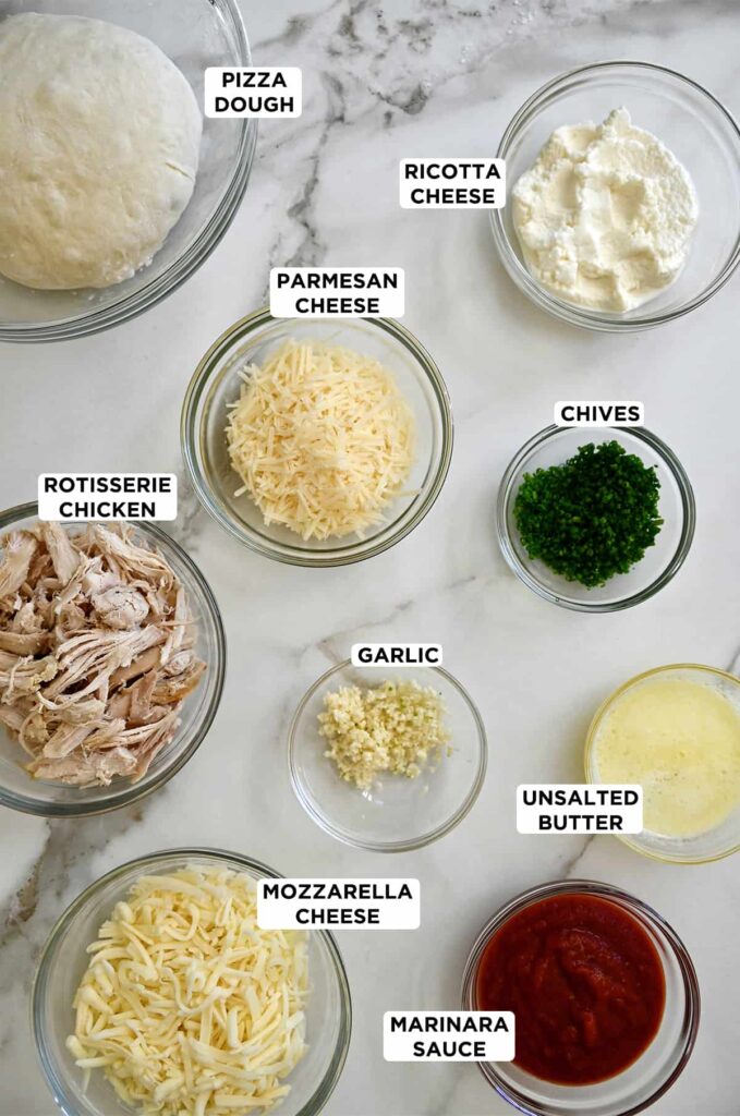Ingredients for homemade pizza: dough, ricotta, parmesan, chives, chicken, garlic, mozzarella, butter, sauce.