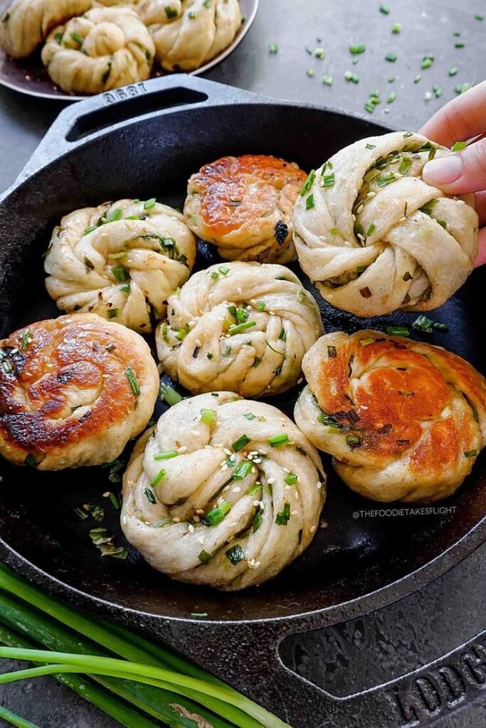 Freshly cooked Chinese scallion pancakes in a cast iron skillet, garnished with chopped green onions.