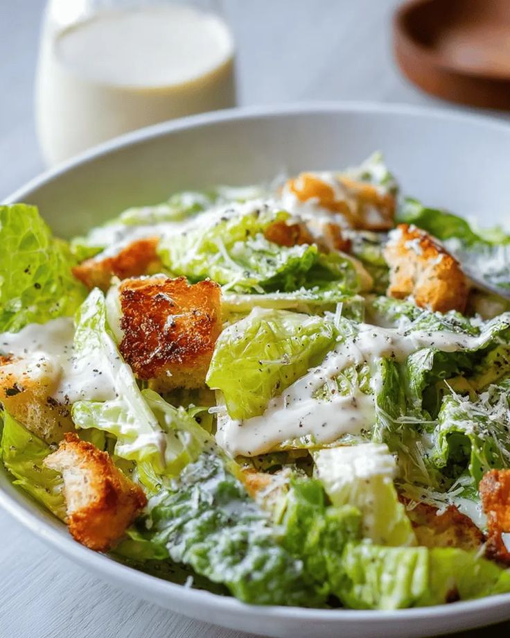 Fresh Caesar salad with croutons, romaine lettuce, parmesan, and creamy dressing in a white bowl.