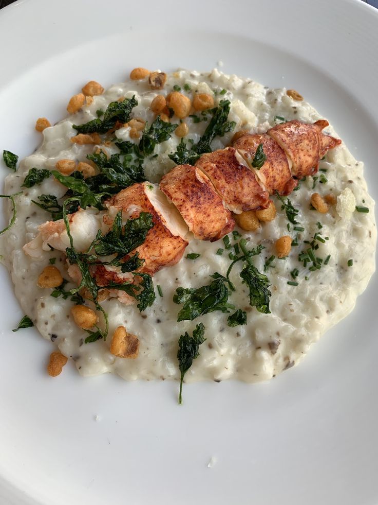 Creamy lobster risotto garnished with herbs and crispy toppings on a white plate.