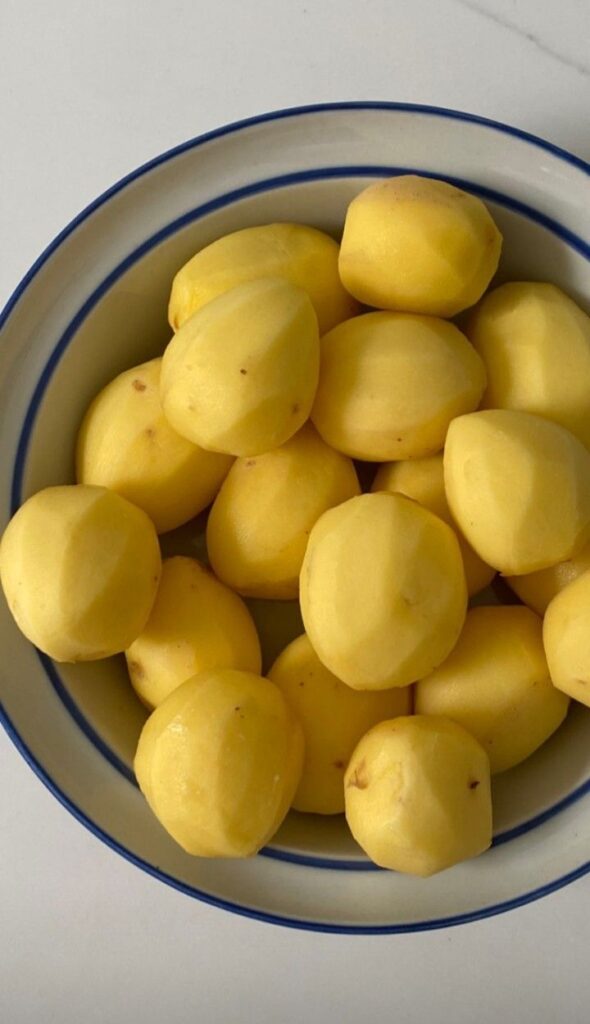 peeled potato yellow bow food healthy organic cooking at home inspo aesthetic moodboard lifestyle hipergamy luxury - Enjoy a French Favorite: Sole Meunière & Potatoes Bowl of peeled potatoes on a white surface, ready for cooking or meal preparation.