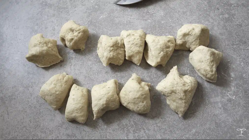 Raw dough pieces on a gray surface, ready for baking preparation.